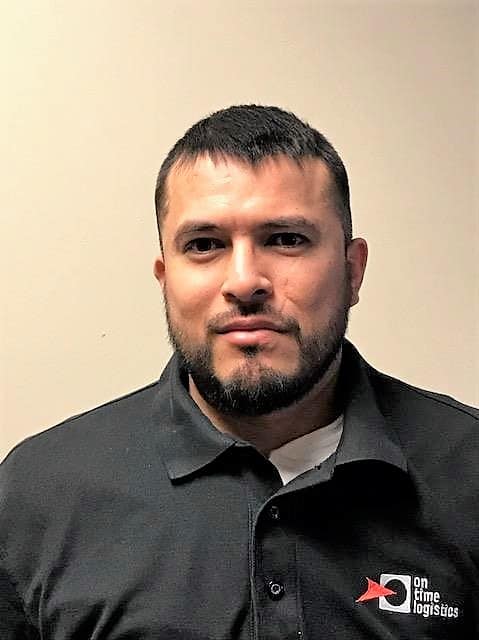 Uriel Espino, part-time driver for On Time Logistics, wearing a company polo shirt, smiling against a neutral background.